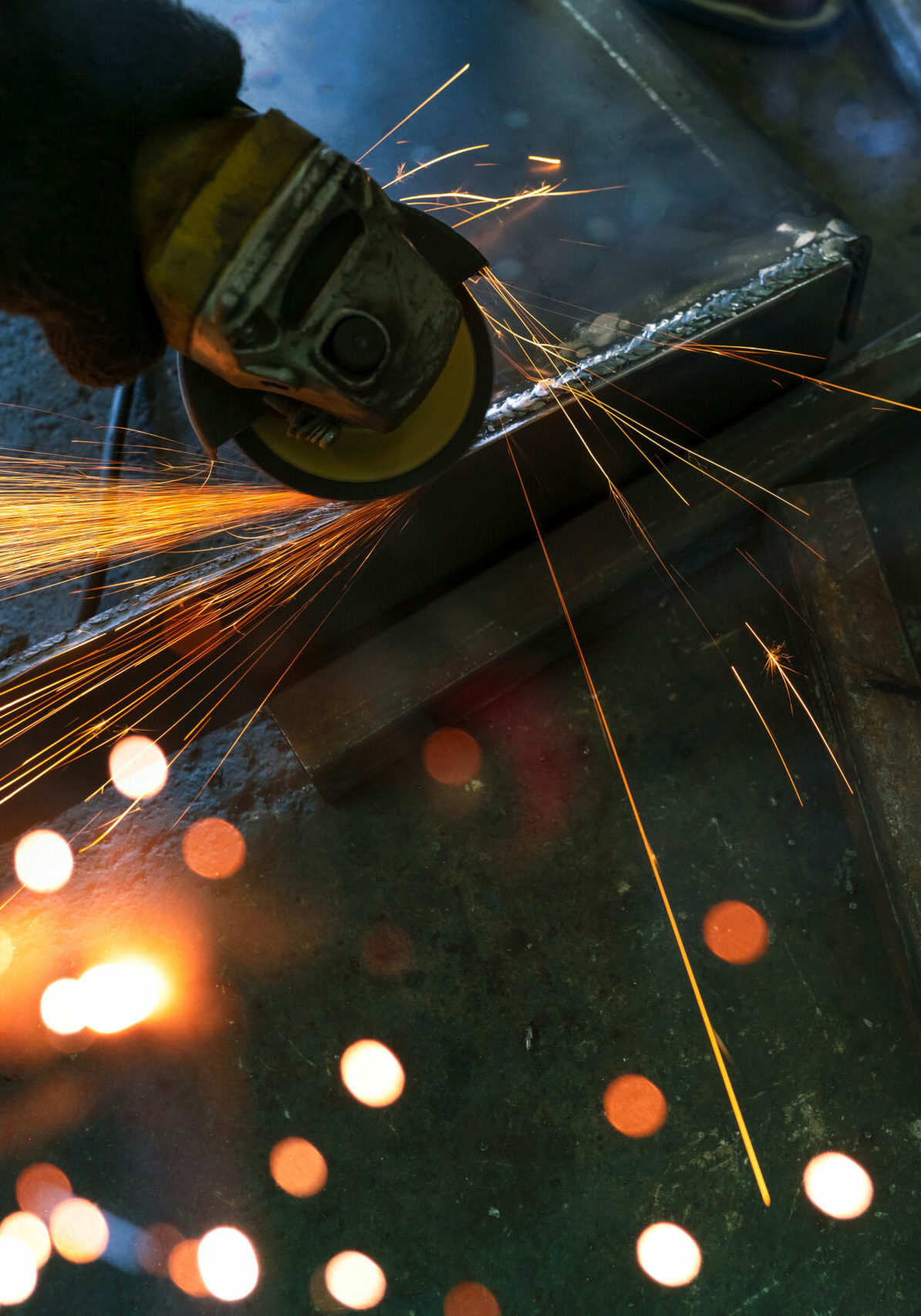 Industrial worker using angle grinder grinding metal on welding seams. Worker working with angle grinder and has sparks. Tool for cut steel. Safety in industrial workplace. Metal factory industry.